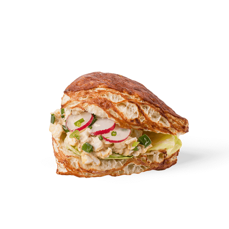 Puszysta bułka francuska z delikatną pastą jajeczną, świeżą sałatą i lekkimi dodatkami warzywnymi. Doskonała propozycja na śniadanie lub lunch, łącząca klasyczny smak z nowoczesnym stylem.

